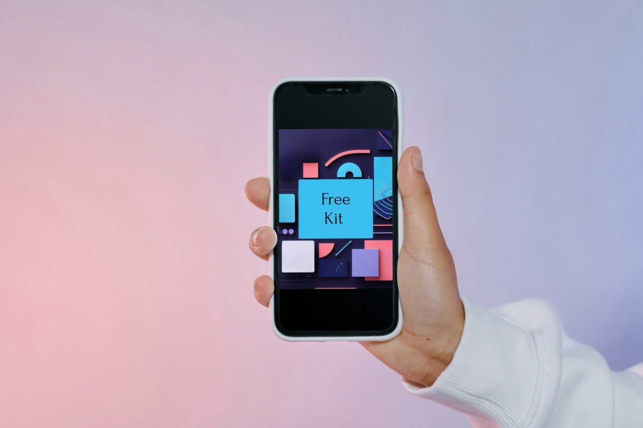 A hand holding a smartphone that displays a colorful app interface labeled 'Free Kit' against a soft pink-to-lavender gradient background.